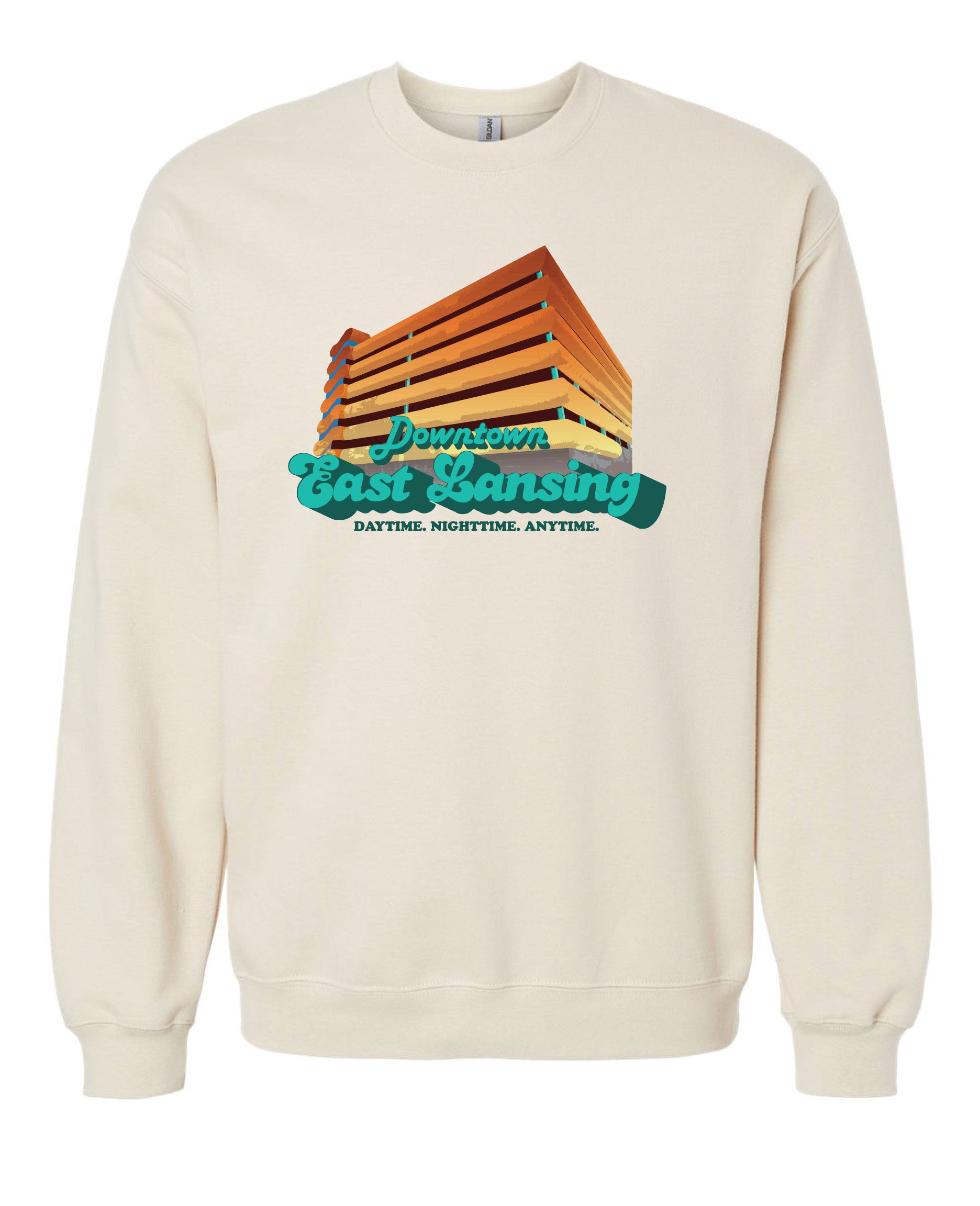 Image is a sand colored (crewneck sweatshirt with an image of the Division Street Parking Garage, a colorful parking garage in downtown East Lansing, on the front side. Beneath the garage, the text “Downtown East Lansing: Daytime. Nighttime. Anytime” is displayed.